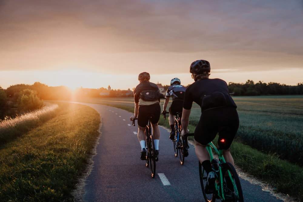 Three cyclists cycling through a nice green environment.